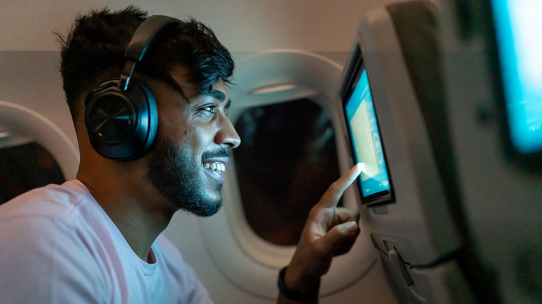 Man wearing wireless headphones using in-flight entertainment