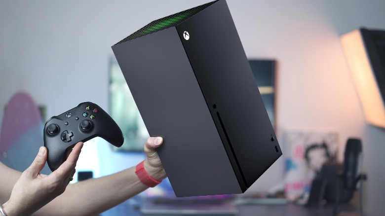 Person holding a black Xbox series X and its controller