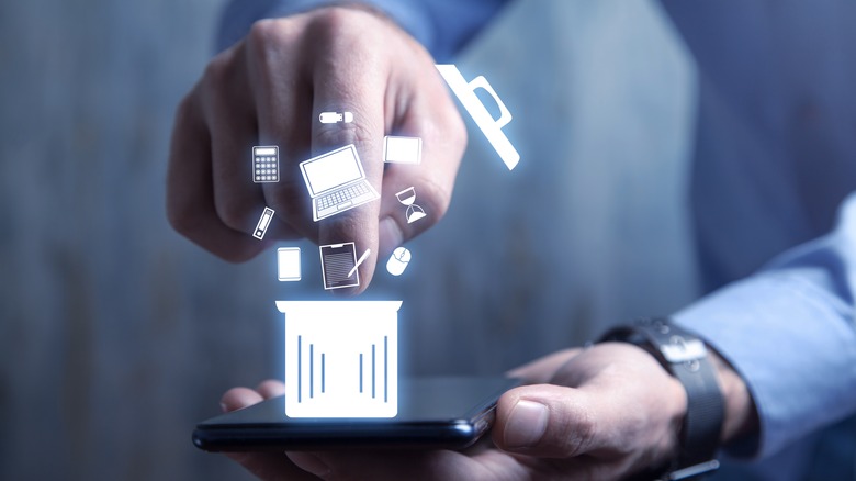 Man's hands holding a phone with laptop, calculator, document, and trash can graphics displayed.