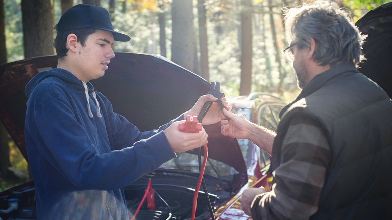 Two Drivers In the Process Of Jump Starting A Car Battery