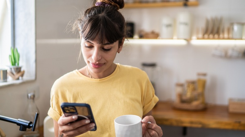 A lady holding mug and iPhone