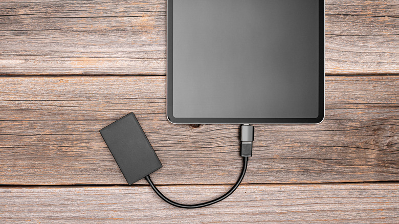 External hard drive connected to an iPad on a wooden table