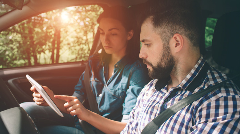 Couple in car looking at tablet screen