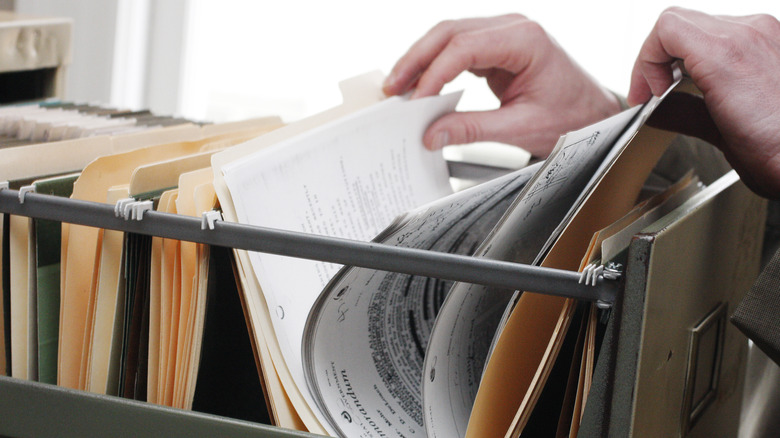 hands flipping through files and folders in a filing cabinet