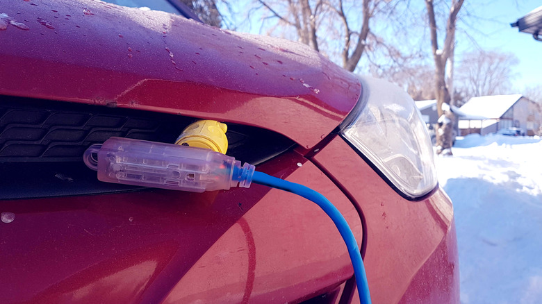 Block heater cable, plugged into a vehicle parked in a snowy winter driveway