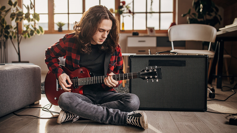 person playing guitar with an amplifier