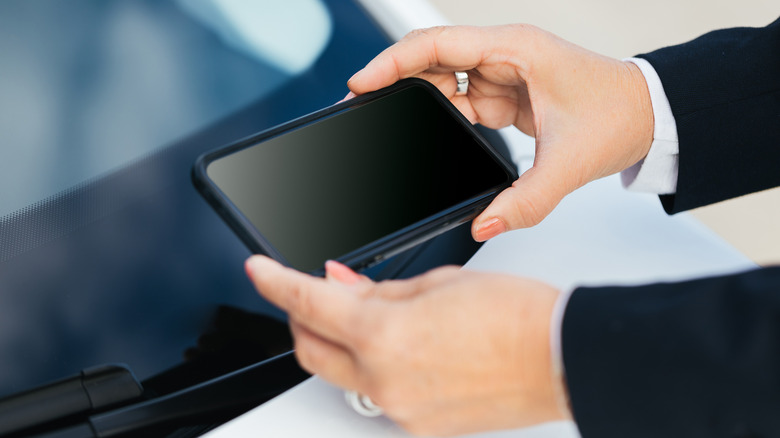 A person using a phone to photograph a car's VIN number.