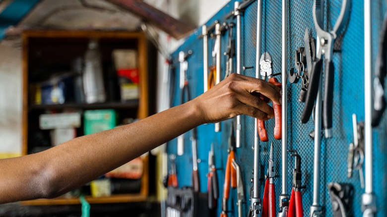 A person's hand reaching for a tool