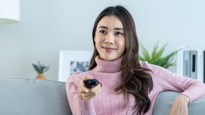 person smiling while pointing TV remote