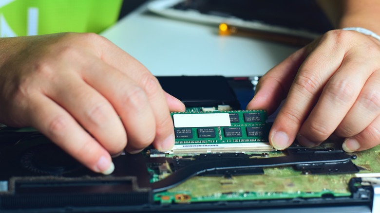 person removing RAM from laptop