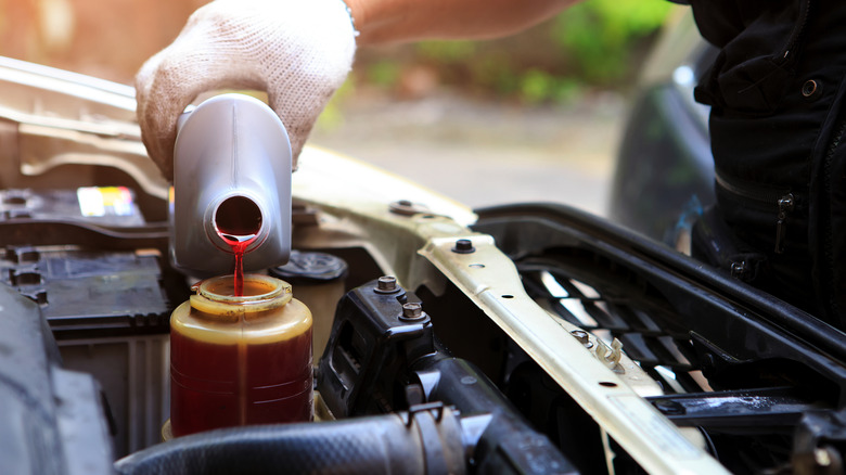 Mechanic refilling the reservoir with fresh power steering fluid