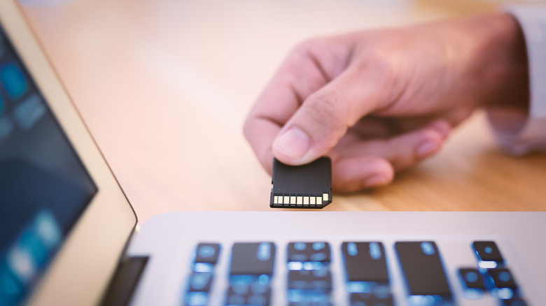 person inserting SD card into MacBook