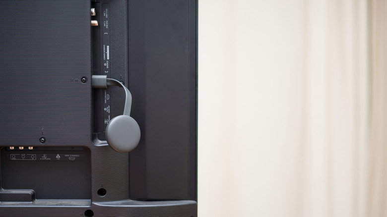 Chromecast device hanging from behind a TV