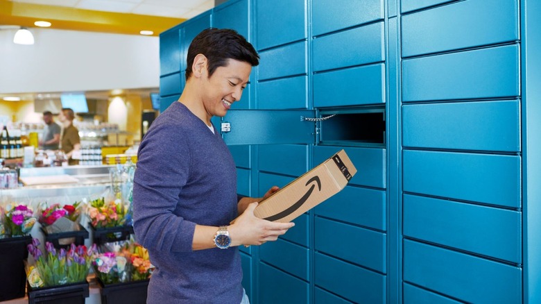 Person smiling next to an Amazon Locker holding a package