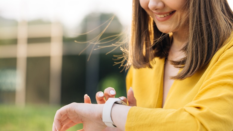 woman smiling while looking at Apple Watch