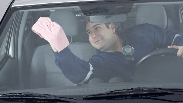 person cleaning inside windshield