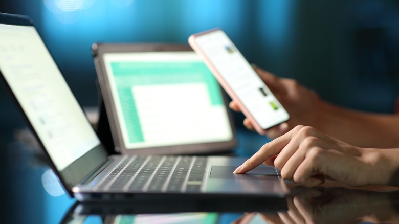 person using laptop and phone simultaneously