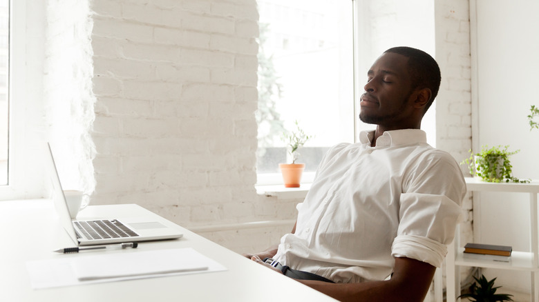 man eyes closed working laptop