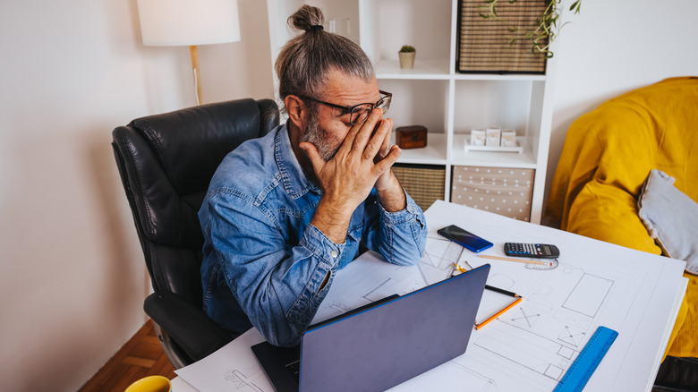 man rubbing eyes home office