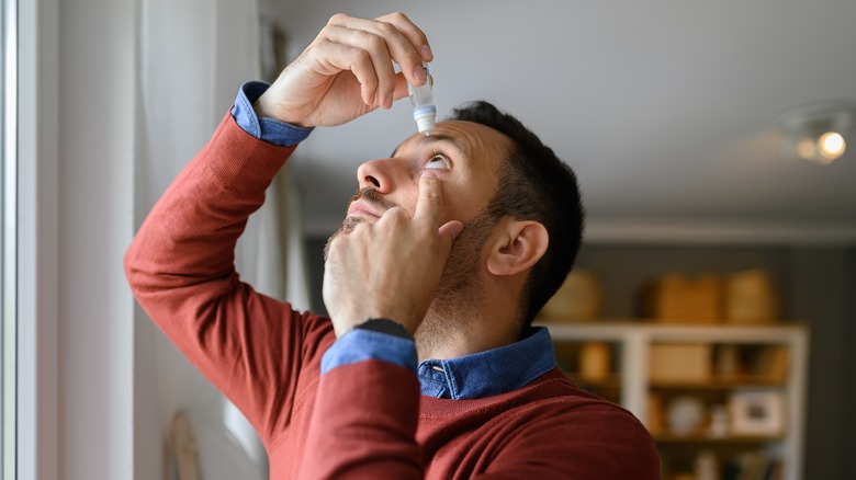 man using eye drops