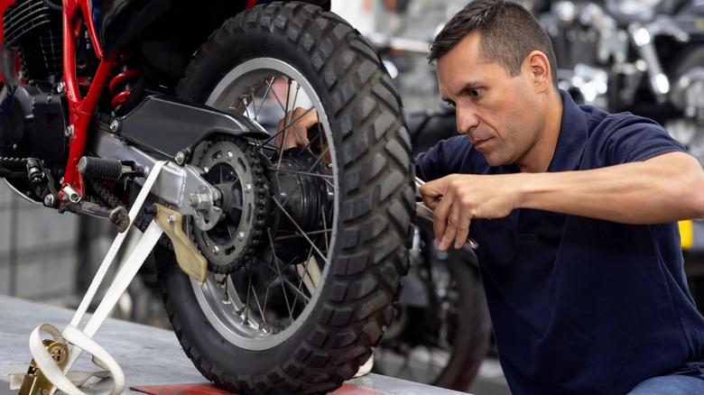 Close-up of mechanic fixing motorcycle tire