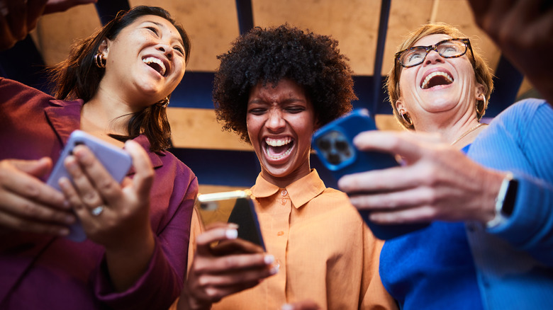 Group holding smartphones and laughing