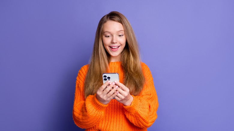 woman holding iPhone in front of purple background