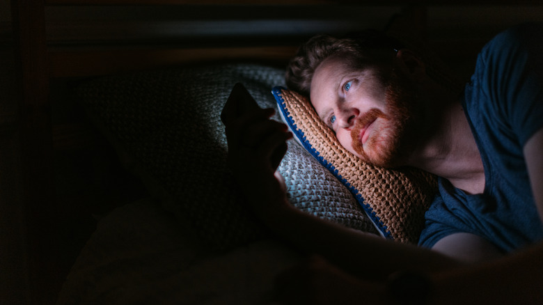 man using bright phone in bed