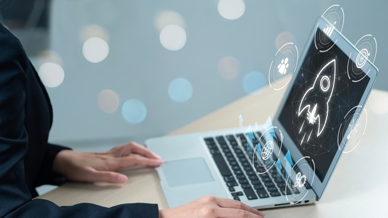 A silver laptop projecting a rocket