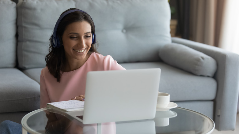 Woman listening to headphones and using laptop