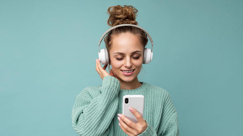 woman listening to headphones and holding smartphone