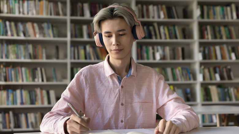 Man listening to headphones in library