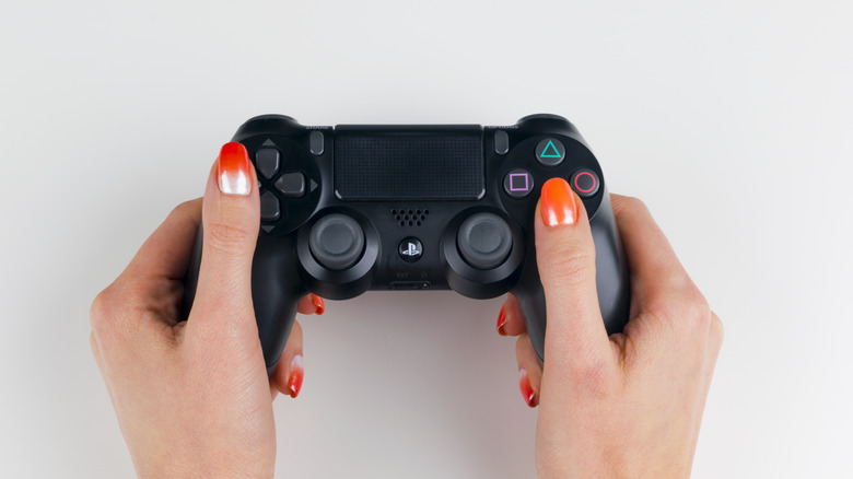 woman with nail polish holding ps4 controller