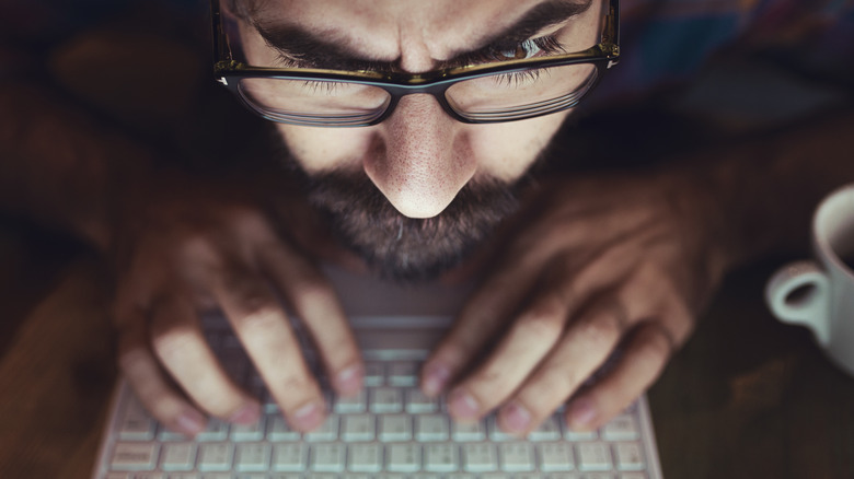 Person with glasses hunched over keyboard