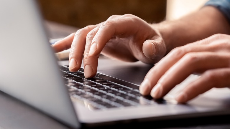 Hands typing on laptop keyboard