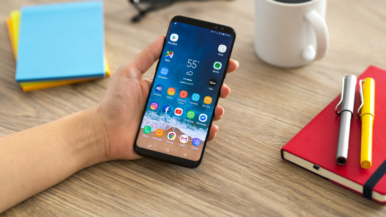 Person holding Samsung phone on desk