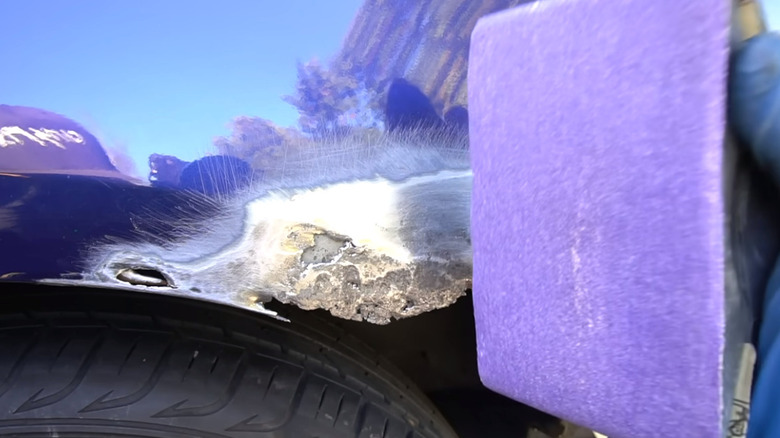 sanding rusted area on blue car