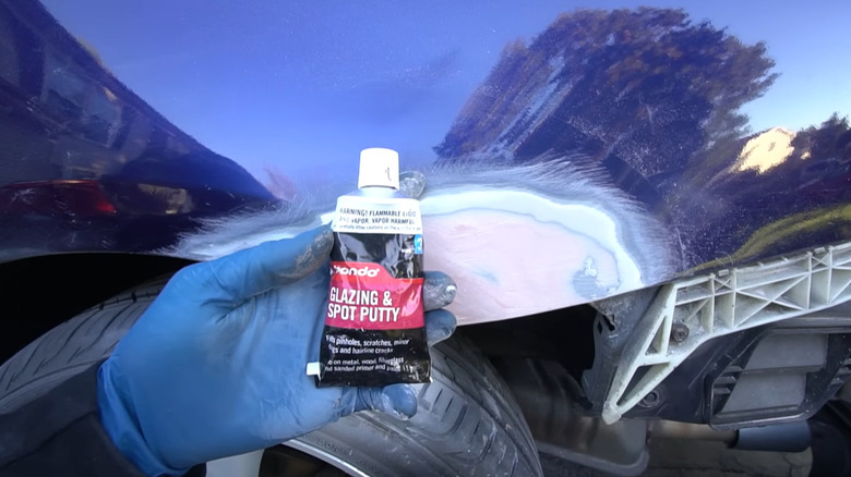 Glazing putty on rust repair on blue car