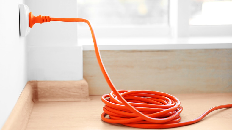 orange extension cord plugged into wall outlet