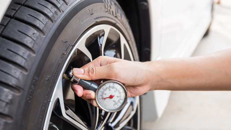 Person using gauge to measure tire pressure