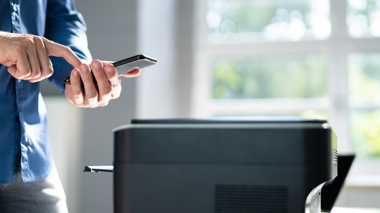 man holding phone near printer