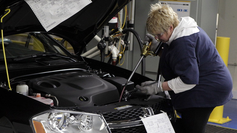 Person filling vehicle transmission fluid