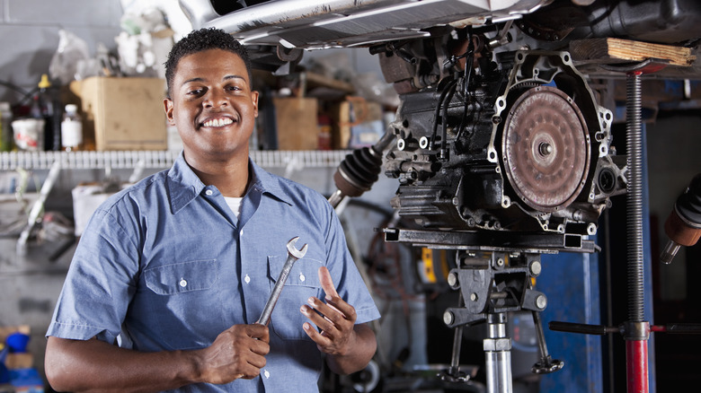 Mechanic stands holding tool