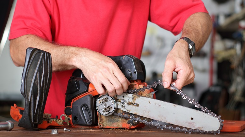 A man loosening the chain on a chainsaw