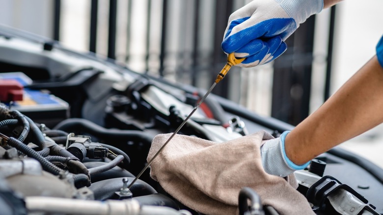 Mechanic checking engine oil level using dipstick