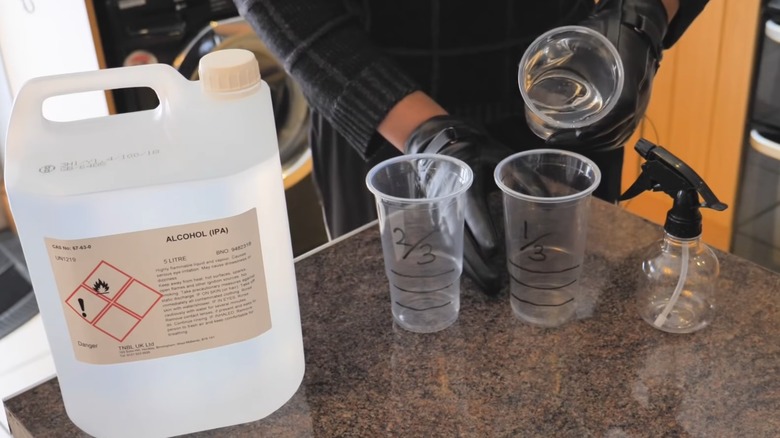 A person making their own car window de-icer with water and alcohol