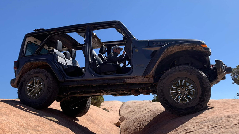 2024 Jeep Wrangler off-roading on rocks, right-hand side view, doors removed