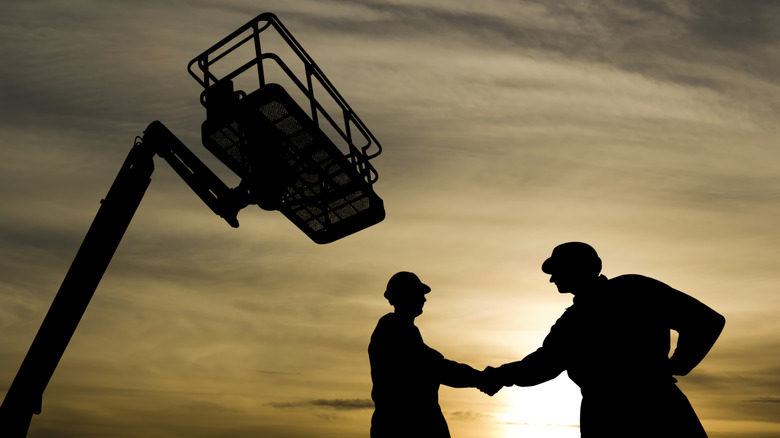 shaking hands near a boom lift