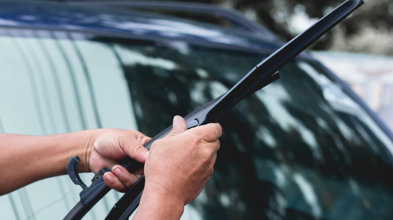 a pair of hands replacing a windshield wiper blade