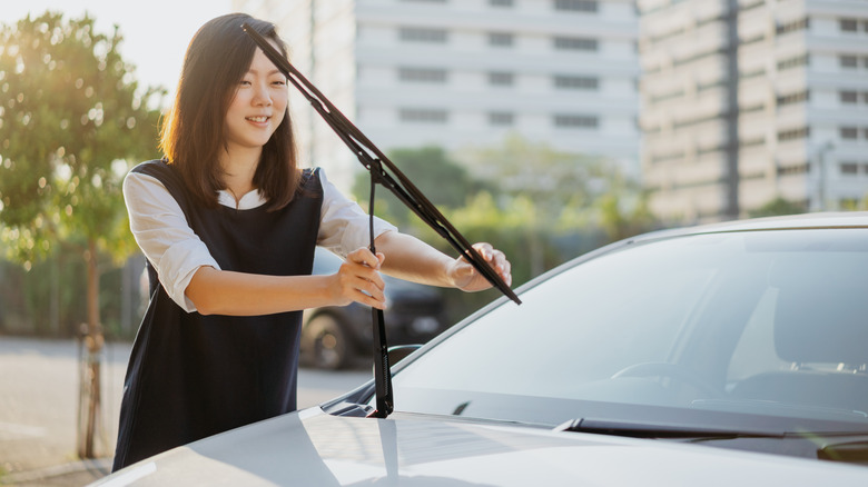 person pulling back and checking a car windshield wiper arm